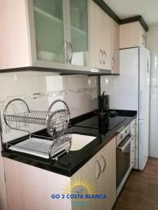 eine Küche mit einer schwarzen Arbeitsplatte und einem Wäscheständer in der Unterkunft Apartamento Torre VII in Benidorm