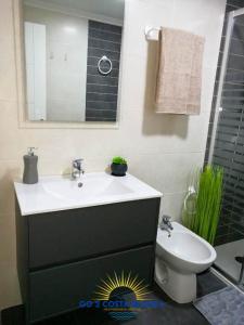 uma casa de banho com um lavatório, um WC e um espelho. em Apartamento Torre VII em Benidorm