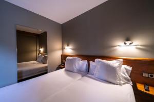 a hotel room with a bed with white pillows at Aparthotel AnyosPark Mountain & Wellness Resort in Anyós