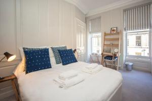 1 dormitorio con 1 cama blanca grande con almohadas azules en Elegant Georgian Maisonette - Central Bath, en Bath