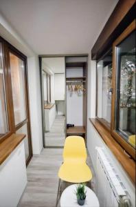 Una silla amarilla en un pasillo con ventanas. en Helia Apartment, en Galaţi
