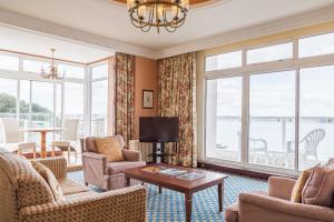 a living room with chairs and a tv and windows at The Imperial Torquay in Torquay