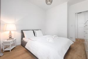 - une chambre blanche avec un lit et une lampe dans l'établissement Apartament Grzybowska 85 Premium by Your Freedom, à Varsovie