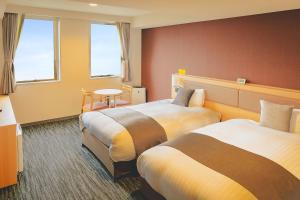 姶良市にあるAIRAIKUHOTEL kagoshimaのベッド2台とテーブルが備わるホテルルームです。