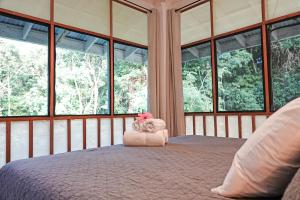 a bedroom with a large bed with windows at Tropical Paradise, Oceanfront Home in the Jungle in Bocas del Toro
