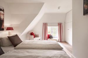 a white bedroom with a bed and a window at Altes Museum Haus 2 in Oevenum
