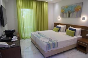 a bedroom with a large bed with green curtains at Loutsiana Deluxe Apts in Ayia Napa
