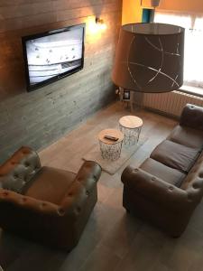 uma sala de estar com 2 sofás e uma televisão de ecrã plano em MAISON AVEC JACUZZI PRIVATIF em Cambrai