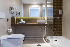 a bathroom with a toilet and two sinks and a shower at Avenida Boutique Hotel in Viseu