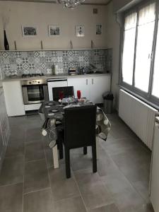 uma cozinha com uma mesa com cadeiras e uma cozinha com um fogão em MAISON AVEC JACUZZI PRIVATIF em Cambrai