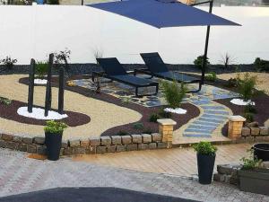 a patio with two chairs and an umbrella at MAISON AVEC JACUZZI PRIVATIF in Saint-Aubert