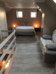 a bedroom with a bed and a couch and two windows at MAISON AVEC JACUZZI PRIVATIF in Cambrai