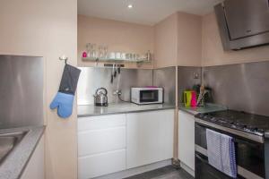 una pequeña cocina con armarios blancos y microondas en ※ Spacious, Central Bath Apartment ※ en Bath