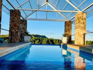 a swimming pool with a glass roof and pillars at Vetho Farmhouse Dullstroom in Dullstroom
