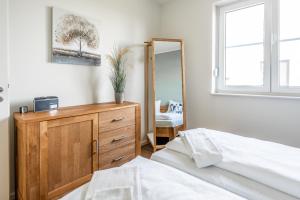 a bedroom with a dresser and a mirror at Hangar 19 Luxusbungalow am See H8 in Schwerin