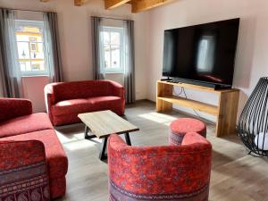 a living room with red chairs and a flat screen tv at Wittichenauer Bleibe in Elsterheide