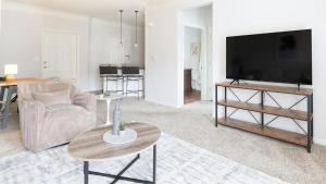 a living room with a tv and a couch and a table at Landing at The Sovereign at Overland Park Apartments - 1 Bedroom in St. Andrews Highlands in Overland Park