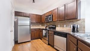 a kitchen with wooden cabinets and stainless steel appliances at Landing at The Sovereign at Overland Park Apartments - 1 Bedroom in St. Andrews Highlands in Overland Park