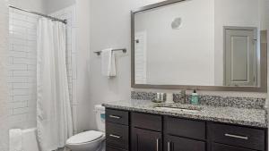 ein Badezimmer mit einem Waschbecken, einem WC und einem Spiegel in der Unterkunft Landing at Three Rivers - 1 Bedroom in Central Fort Wayne in Fort Wayne