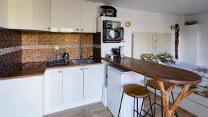 une cuisine avec des placards blancs et un comptoir en bois dans l'établissement Maisonnette cosy bord de Seine 30min paris, à Carrières-sous-Poissy