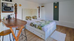 - une chambre avec un lit, une table et un bureau dans l'établissement Maisonnette cosy bord de Seine 30min paris, à Carrières-sous-Poissy