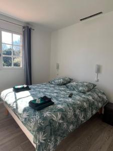 a bedroom with a bed with a green comforter at Hôtel Restaurant La Tonnelle in Mios +1 photo