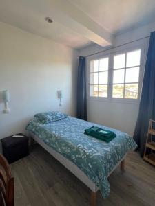 una camera da letto con un letto con un piumone blu e una finestra di Hôtel Restaurant La Tonnelle a Mios