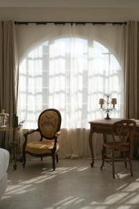 a room with a chair and a table and a window at L'Abbaye Hôtel in La Colle-sur-Loup