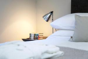 a bed with a lamp and a pile of books at Stylish Wood Street Apartment in Bath