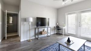 a living room with a flat screen tv and a table at Landing at Mission Hill - 1 Bedroom in New Braunfels in New Braunfels