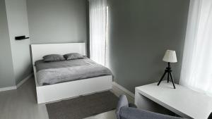 a white bedroom with a bed and a chair at Apartament MARIA z ogródkiem i parkingiem in Śrem
