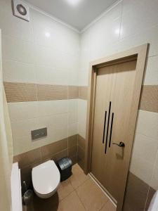 baño con aseo y puerta de madera en 2 комнатная за Хан шатыром левый берег en Taldykolʼ