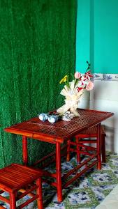 een houten tafel met een vaas met bloemen erop bij Cần Thơ Farmstay in Can Tho