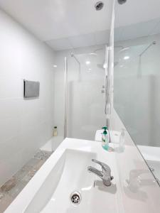 a white bathroom with a sink and a shower at Gran Teatro Falla in Cádiz