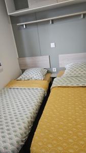 dwa łóżka siedzące obok siebie w pokoju w obiekcie Mobil home les sables d'or w Cap d'Agde