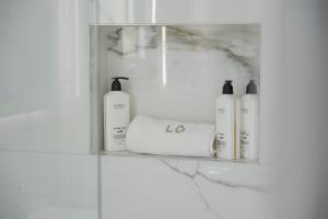 a shelf with four bottles of soap and towels at Loutsiana Deluxe Apts in Ayia Napa
