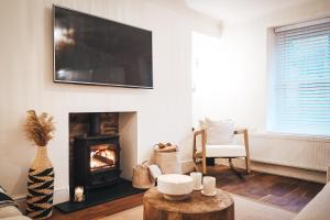a living room with a fireplace and a flat screen tv at Pye Corner Cottage, by Solace Stays in Bellaghy
