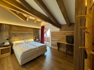 1 dormitorio con 1 cama y pared de madera en Hotel Al Lago, en Lavarone