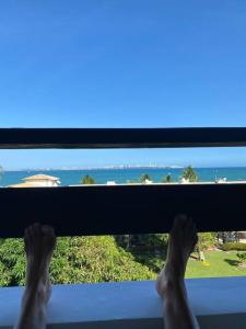 a persons feet on a window looking out at the ocean at Flat aconchegante à beira-mar in Vera Cruz de Itaparica