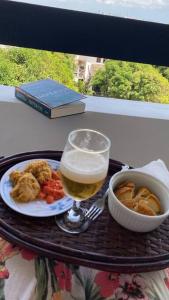 ein Tablett mit einem Glas Bier und einem Teller Essen in der Unterkunft Flat aconchegante à beira-mar in Vera Cruz de Itaparica