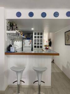 a kitchen with two stools in front of a counter at Flat aconchegante à beira-mar in Vera Cruz de Itaparica
