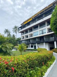 um grande edifício de apartamentos com um jardim e palmeiras em Flat aconchegante à beira-mar em Vera Cruz de Itaparica