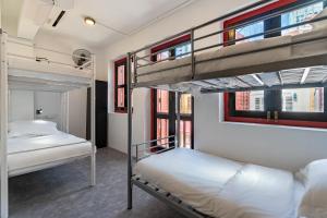 two bunk beds in a room with windows at Rucksack Inn Temple Street in Singapore