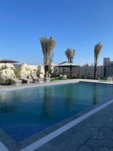 una grande piscina con palme e un edificio di شاليه لحظات a Āsam