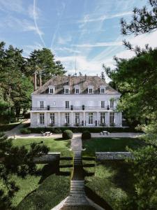 una grande casa bianca con giardino e alberi di Domaine du Chesney a Pressagny l'Orgueilleux