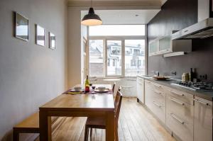 une cuisine avec une table en bois et une grande fenêtre dans l'établissement Grand appartement d'artiste cosy et proche de tout, à Bruxelles