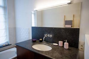 La salle de bains est pourvue d'un lavabo et d'une baignoire. dans l'établissement Grand appartement d'artiste cosy et proche de tout, à Bruxelles