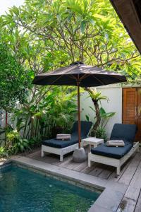 スミニャックにあるThe Gardens Seminyakのパティオ(パラソル、椅子付)、プールが備わります。