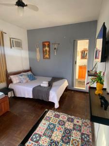 Schlafzimmer mit einem Bett, einem TV und einem Teppich in der Unterkunft Casa de Praia Suítes in Saquarema