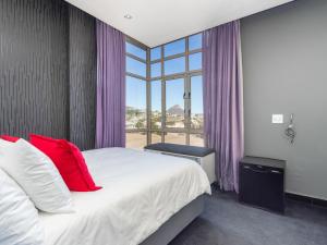 a bedroom with a bed with red pillows and a window at Upper East Side 407 in Cape Town